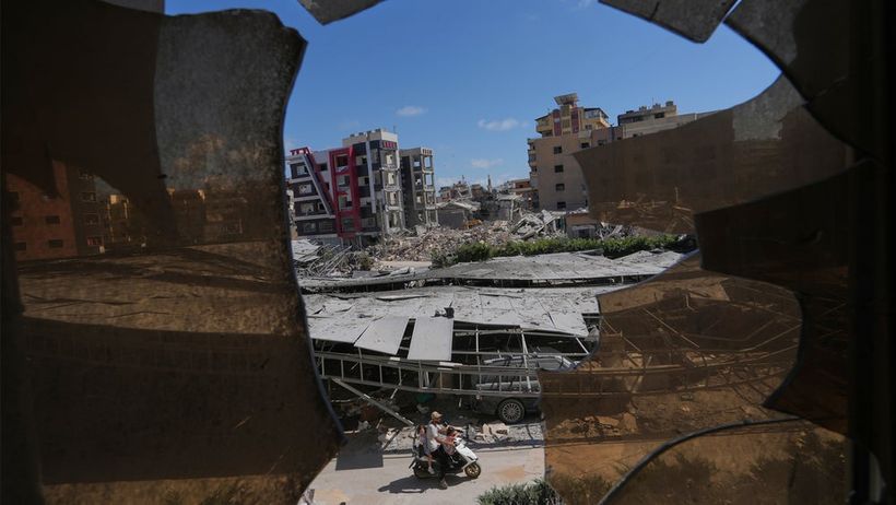 Buildings damaged by Israeli strikes are seen through shattered glass from the Jabal Amel Hospital in the southern port city of Tyre, Lebanon, Thursday, June 18, 2026. (AP Photo/Hassan Ammar) HAS130