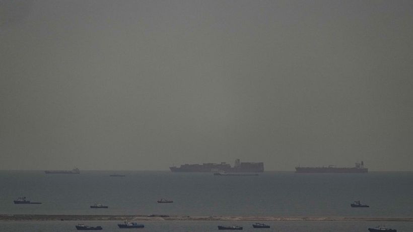 Fishing boats dot the sea as cargo ships, in the background, sail through the Arabian Gulf toward the Strait of Hormuz off the United Arab Emirates, Friday, March 27, 2026. (AP Photo) AQX104
