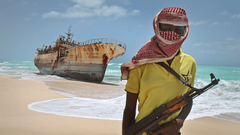 En somalisk pirat står vid ett taiwanesiskt fiskefartyg som spolats upp på stranden i Hobyo, Somalia, 2012. Bilden togs i den då ökända pirathamnen, där besättningen hade släppts efter att en lösensumma betalats.
