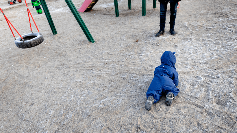 Barn kryper på lekplats vid förskola. 